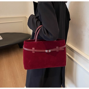 Macro view of burgundy velvet tote bag with fine stitching and silver metal buckle