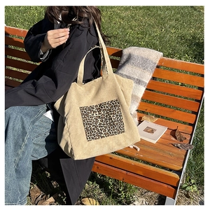 Close-up of beige corduroy tote bag with leopard print pocket in outdoor casual setting