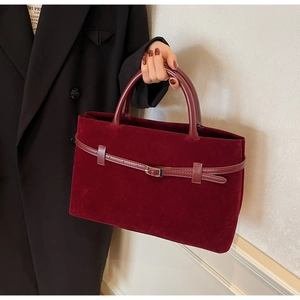 Detailed texture of burgundy velvet tote bag featuring a decorative strap and silver buckle