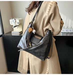 Detail view of large black leather hobo bag with adjustable strap and baseball charms
