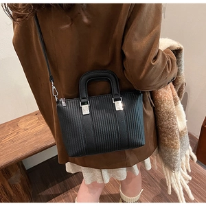Detail of black pebbled leather bucket bag with silver hardware and stripe texture