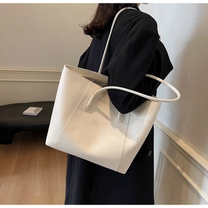 Detail of minimalist cream large tote bag with elegant V-shaped stitching and slim straps