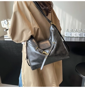 Model view of black leather tote bag with gold metal buckle in cozy cafe setting