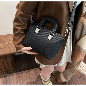 Detail view of black bucket bag with vertical stripe embossing and silver metal hardware
