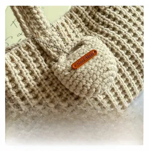 Close-up of oatmeal knit tote bag with handmade leather label and mini coin purse