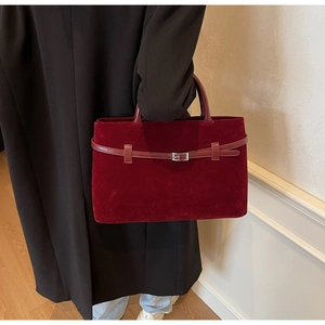 Detail of burgundy frosted suede tote bag featuring silver buckle and round handle