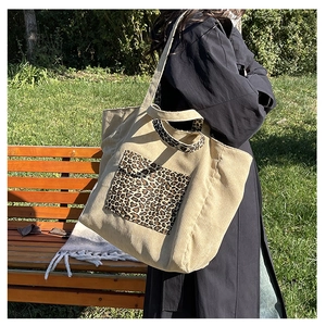 Detail of beige corduroy tote bag featuring leopard print pocket and sturdy handles