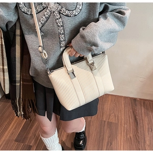 Detail view of cream pleated bucket bag with metal buckle and adjustable strap