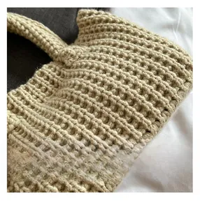 Macro view of handmade beige knitted handbag showing detailed thick crochet texture