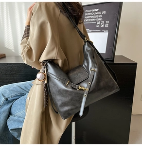 Detail of vintage gray tote bag in soft leather with buckle straps and a baseball charm