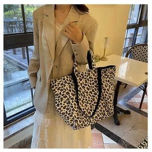 Leopard print canvas tote bag shown as a side view worn by a model in a cafe