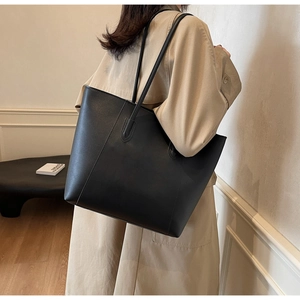 Minimalist black matte leather tote bag styled with beige trench coat for office commute