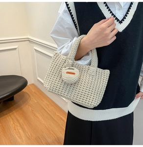 Close-up of cream knit bucket bag showing textured crochet and Hand Made leather tag