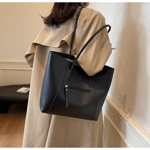 Close-up of black matte leather tote bag with exterior zipper pocket worn by a model