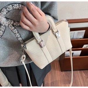 Detail of beige pleated shoulder bag with silver hardware and adjustable leather strap
