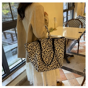 Leopard print canvas tote bag on female model shoulder in a casual cafe setting