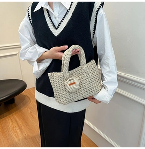 Detailed view of beige hand-knit bucket bag with heart pendant and leather tag