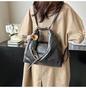 Detail of vintage black faux leather backpack with gold hardware and baseball charm