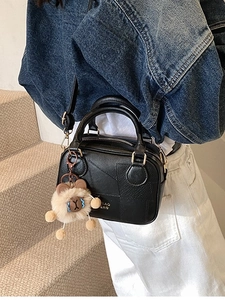 Retro black leather crossbody bag with teddy bear charm and adjustable strap shown on model