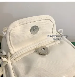 Close-up of the magnetic closure on a minimalist white canvas crossbody phone bag