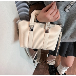 Detailed side view of off-white pleated bucket bag worn with a stylish preppy outfit