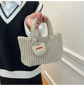 Detail view of cream handmade crochet bucket bag with textured weave and leather tag