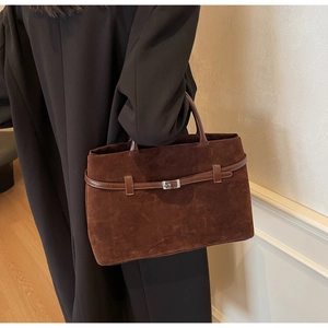 Macro detail of dark brown matte suede tote bag with silver buckle and leather strap
