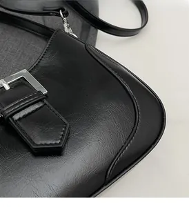 Close-up of black oil-wax textured leather handbag with silver metallic buckle detail
