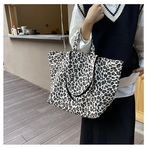 Close-up of leopard print canvas tote bag carried by a model in a natural outdoor setting