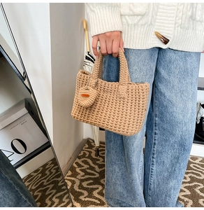 Detailed knit texture of beige crochet bucket bag with a heart-shaped charm accessory