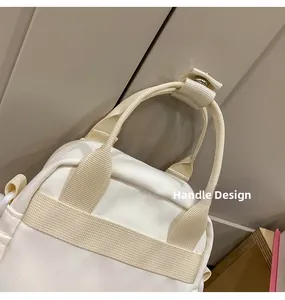 Close-up of the reinforced canvas handle and metal hardware on the cream crossbody bag