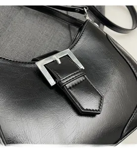 Detailed macro view of glossy black pleated leather texture and silver square metal buckle