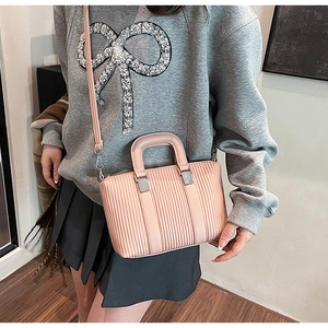 Detail view of pink pleated bucket bag with silver hardware and long shoulder strap