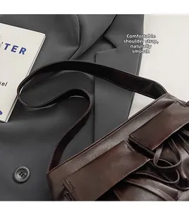Detail of soft wide shoulder strap and dark brown glossy leather of the baguette bag