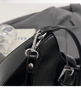 Detail of silver hardware and stitching on black leather underarm shoulder bag