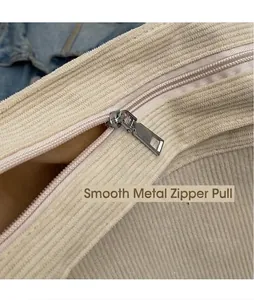 Dettaglio della cerniera in metallo liscio su una borsa tote in velluto a coste beige