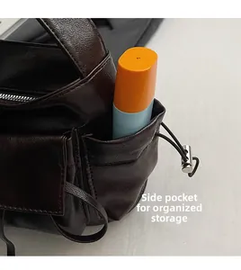 Detail view of the side pocket on a brown leather shoulder bag showing storage space