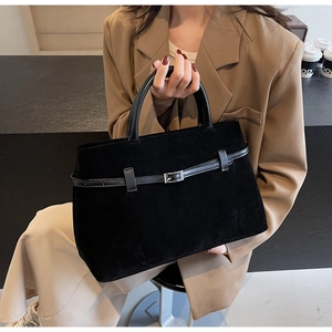 Macro shot of matte black tote bag showing silver buckle belt detail and soft suede texture