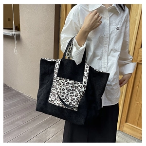 Detail of black corduroy tote bag featuring leopard print pocket on model shoulder