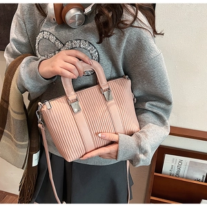 Close-up of pink pleated tote bag with silver hardware on a casual model outfit