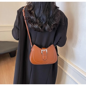 Caramel brown leather saddle bag with silver buckle worn over a black blazer jacket