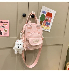 Detailed view of a pink nylon mini bag with plush puppy charm and lucky patch