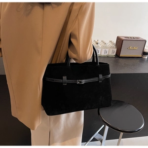Lifestyle shot of large black suede tote bag with metal buckle worn with a beige blazer