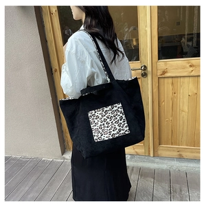Detail of black corduroy tote bag featuring a leopard print pocket and patterned strap