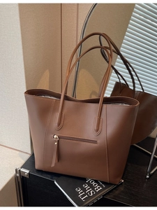 Brown leather tote bag with double shoulder straps and a hidden front zipper pocket