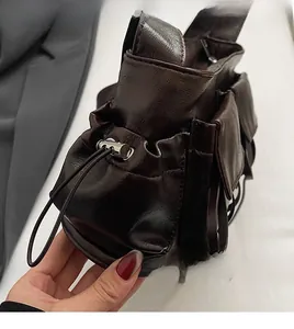 Detail of dark brown waxed leather bag with metallic drawstring lock and utility pocket