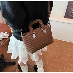 Detailed side view of a brown pleated bucket bag with silver hardware on a person