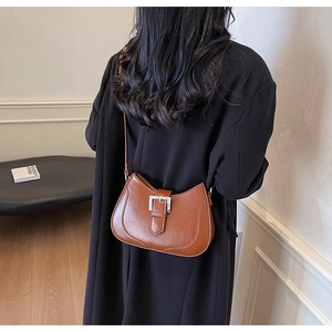 Detail view of brown vintage crescent shoulder bag with silver buckle on female model