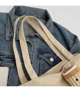 Dettaglio della borsa tote in velluto a coste crema con tracolla liscia e charm peluche