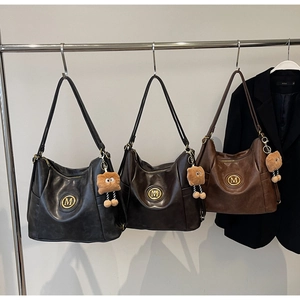 Detailed close-up of three vintage leather tote bags with M-logo and plush charms